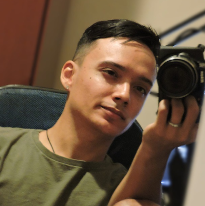 Foto do Integrante João Vitor, ele tem cabelo curto, liso e está com uma camera em que fotográfica.